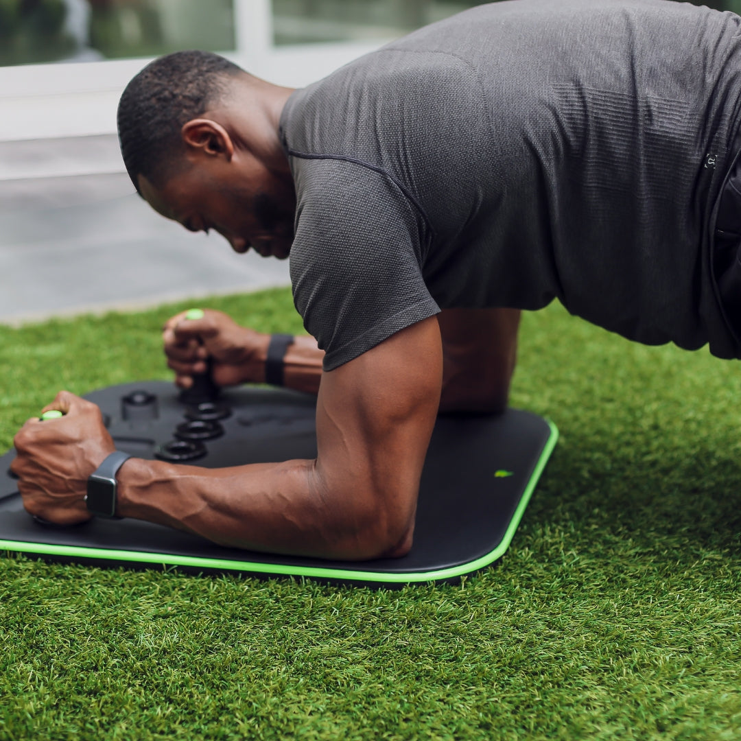 Man exercising on a mat outdoors, performing a plank.